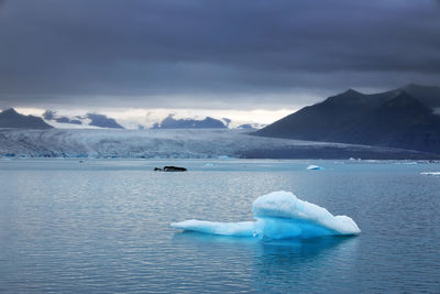 Scenic view of iceberg in lagoon against sky