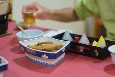 Cropped image of person having beer with food on table