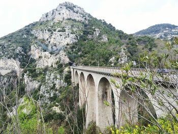 Bridge over mountain against sky