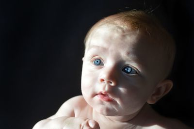 Close-up of cute baby boy looking away in darkroom