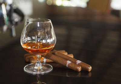 Close-up of whiskey in glass by cigars on table in restaurant