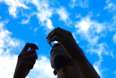 Low angle view of man photographing against blue sky