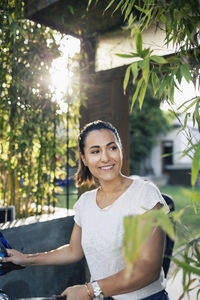 Happy woman looking away while holding bicycle outdoors