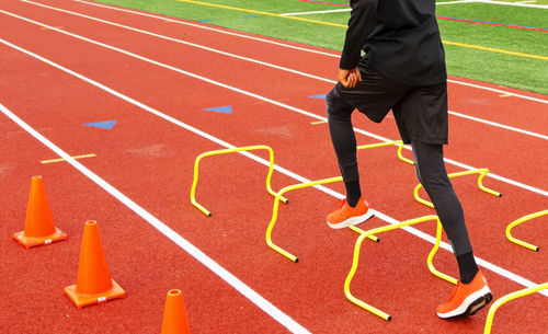 Athlete running over small hurdle on track field