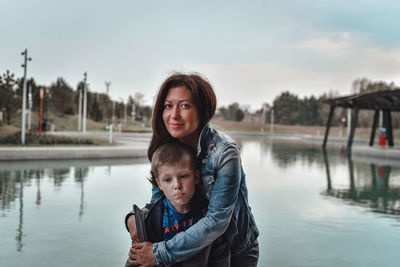 Portrait of mother and son in lake against clear sky