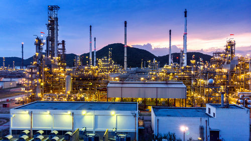 Illuminated factory against sky at night