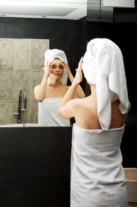 Reflection of woman wearing towel in mirror at bathroom