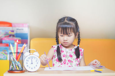 Close-up of cute girl sitting by table