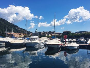 Boats moored at harbor against sky