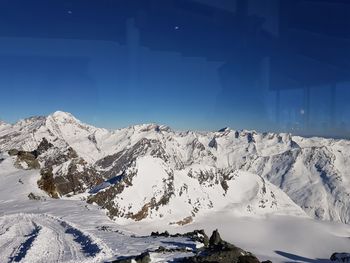 Scenic view of snowcapped mountains against blue sky