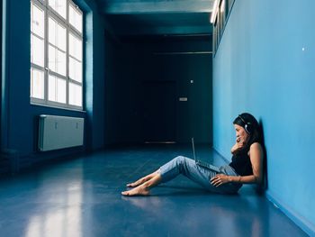 Side view of businesswoman using laptop while sitting on floor in startup office