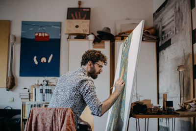 Rear view of man painting on canvas at home