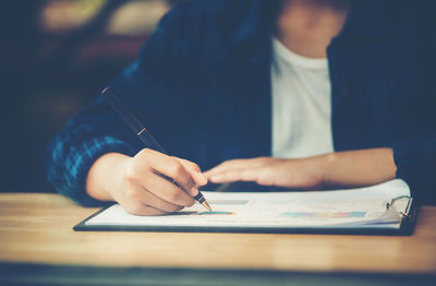 Midsection of man reading book on table