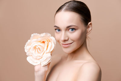 Portrait of young woman with rose against white background