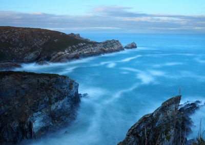 Scenic view of sea by rock formation against sky