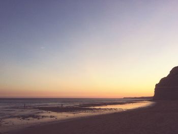 Scenic view of beach against clear sky during sunset