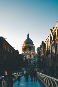 Group of people walking in building against clear sky