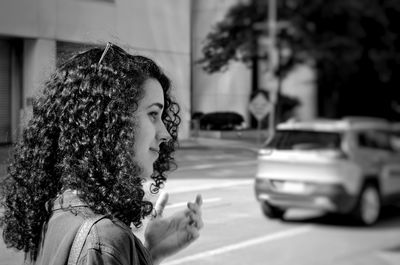 Smiling young woman with curly hair on city street
