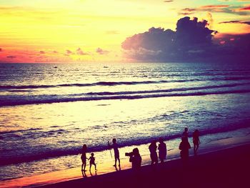 Silhouette of people on beach at sunset