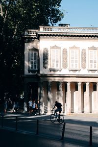 People riding bicycle on road by building