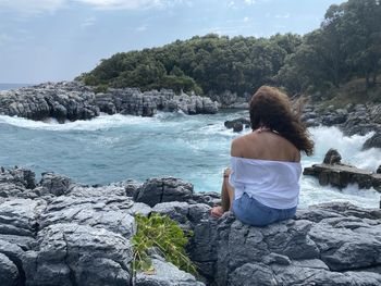 Girl is watching the waves crushing on the rocks 