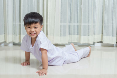 Portrait of boy cheerful boy lying against curtain at home