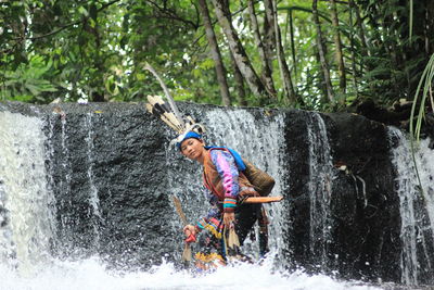 Portrait of woman wearing traditional clothing standing in waterfall