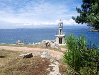 Lighthouse by sea against sky