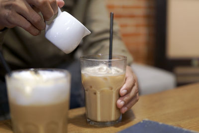 Cropped hands of man preparing iced coffee on table