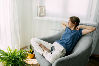 An overworked girl is sitting in a chair, resting, stretching her arms with her eyes closed