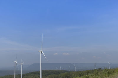 Wind turbines on field against sky