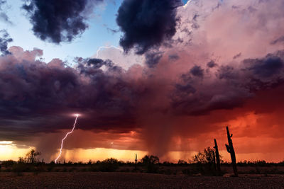 Panoramic view of lightning over field against dramatic sky during sunset