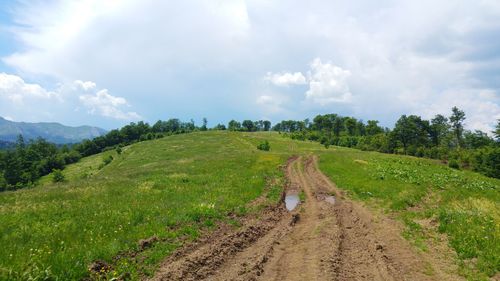 Panoramic view of road amidst field against sky