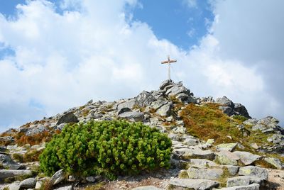 Low angle view of cross on rock against sky