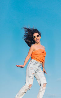 Low angle view of woman against blue sky