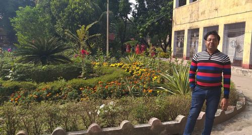 Portrait of young woman standing by plants