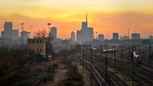 High angle view of railroad tracks by buildings against sky during sunset