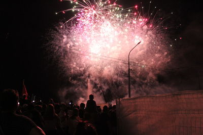 Silhouette people against firework display at night