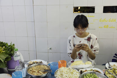 Young woman sitting over food and using phone