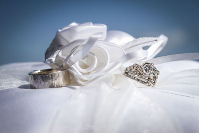 Close-up of wedding rings by artificial rose on pillow