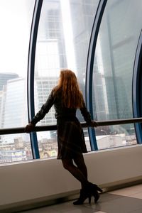 Rear view of woman standing by railing in modern building
