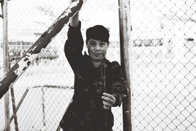 Portrait of man standing by chainlink fence