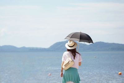 Rear view of man standing by sea