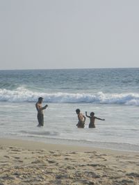 People on beach against clear sky