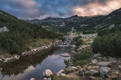 Scenic view of river by mountains against sky