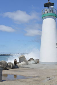 Lighthouse on beach against sky