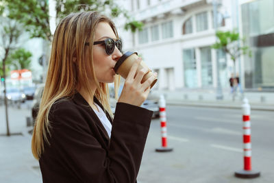 Portrait of woman wearing sunglasses against city