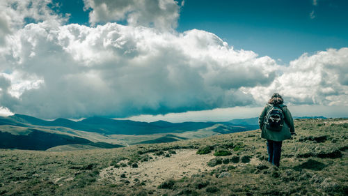Rear view of man standing on mountain against sky