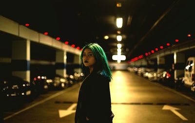 Young woman standing on illuminated walkway at night