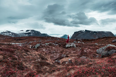 Mid distance of woman standing on grassy field against cloudy sky